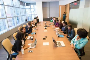 Well-lit conference room with 30 people sitting at the table.