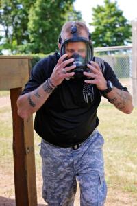 An officer in training with a gas mask on their face as they run through an obstacle course