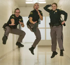 three lady sheriffs jumping for joy in the air
