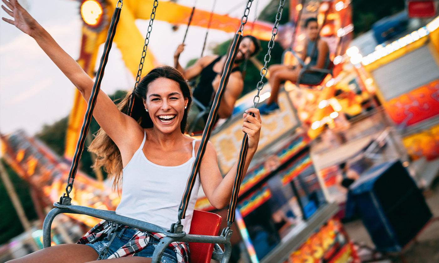 Girl riding swing at festival and laughing