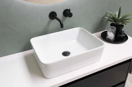 Modern bathroom with a white vessel sink, black wall-mounted faucet, centered black drain, and sleek design against a muted green wall