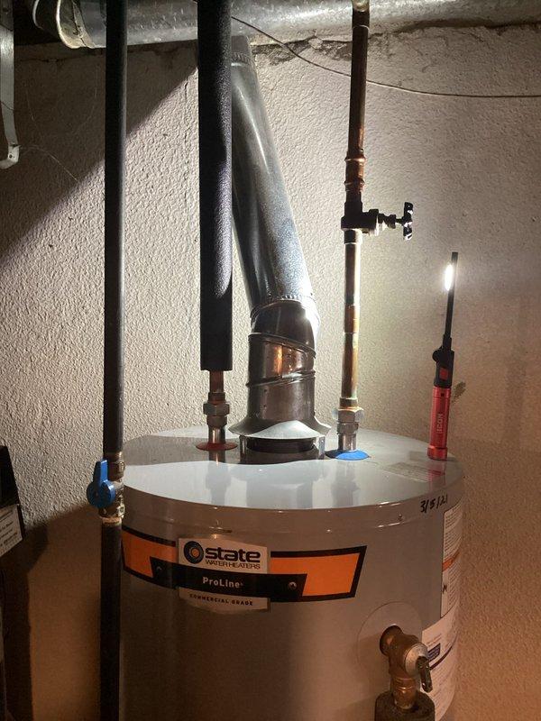 Diagnosed 5-year-old State ProLine water heater with active tank leak from bottom seam, evidenced by significant corrosion buildup. Visual inspection confirmed terminal tank failure requiring complete replacement; temporary measures not viable due to compromised tank integrity. Documented condition with photos for customer reference and warranty purposes.