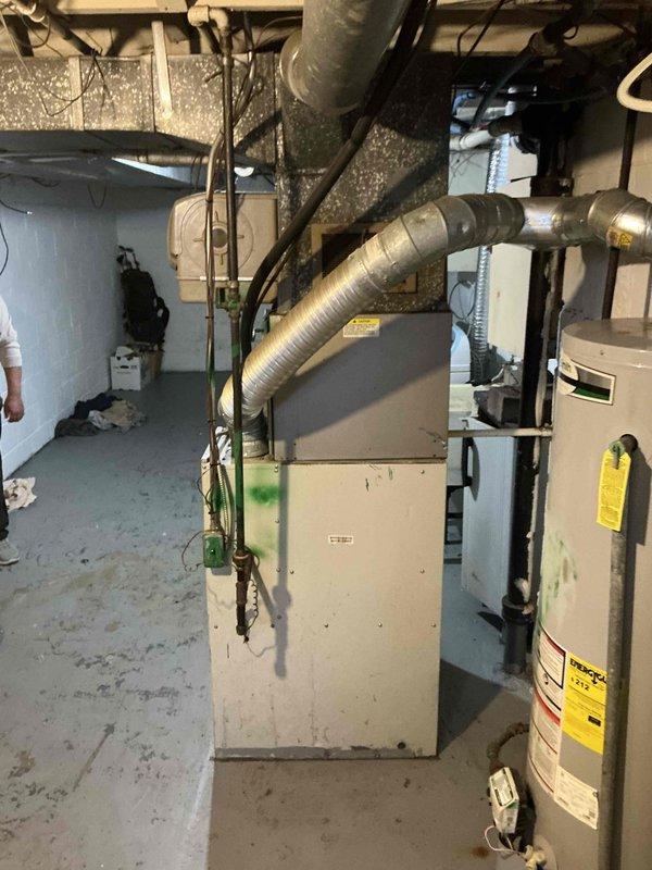Conducted a comprehensive assessment of an aging forced air HVAC system located in a basement utility room. Evaluated the existing furnace unit with connected ductwork and documented the current installation conditions including adjacent water heater and available utility connections. Provided replacement options in accordance with the customer's interest in the BOGO promotion, with recommendation for prompt system replacement.