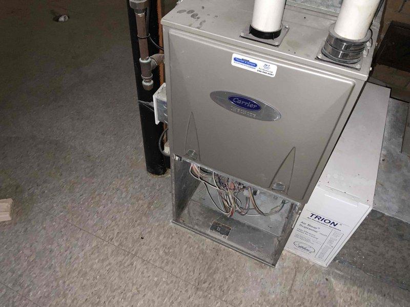 Conducted assessment of aging furnace and hot water tank system located in unfinished basement. Unit is currently operational but at end of serviceable life. Documented existing Carrier furnace setup with TRION air filtration component, PVC venting, and associated ductwork configuration for replacement quote purposes.