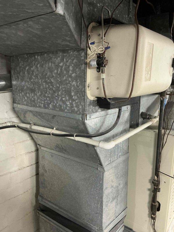 Conducted comprehensive evaluation of 16-year-old HVAC system including furnace and air conditioning unit. Documented existing galvanized metal furnace with attached humidifier, ductwork configuration, and drainage setup. Assessed outdoor unit placement constraints between fence and vegetation. Recommended full system replacement based on age and customer's desire for proactive replacement before failure occurs.