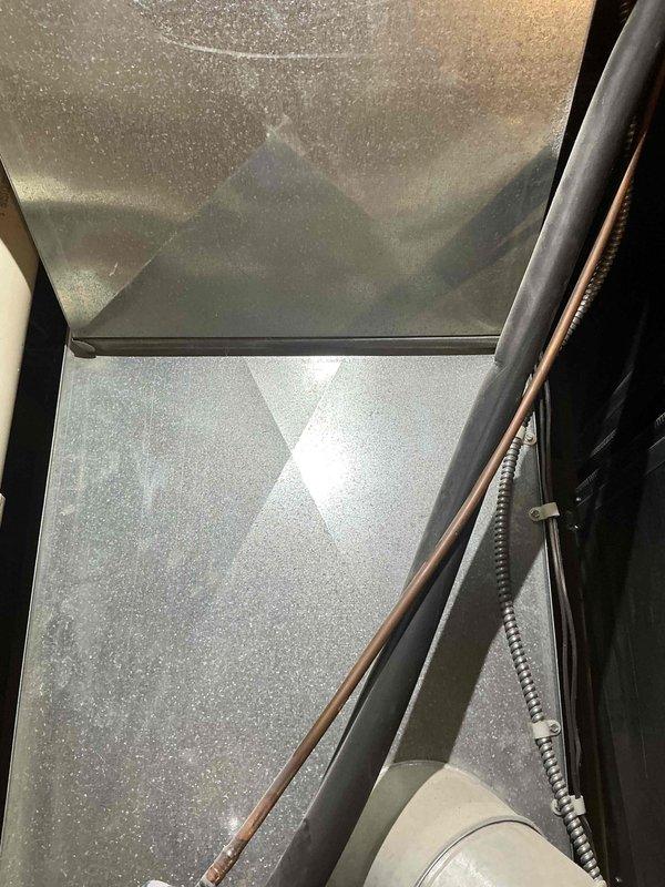 Conducted inspection of a 2003 basement HVAC system with compromised heat exchanger that is barely operational. Documented existing installation including PVC venting configuration and interior furnace compartment with visible copper refrigerant lines. Provided replacement estimate for furnace and A/C system to address end-of-life equipment concerns.