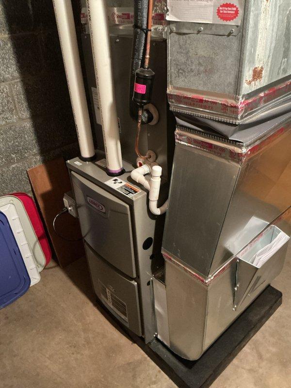 Performed annual maintenance on Lennox furnace system in basement utility area. Inspected and cleaned unit components, checked ductwork connections noting some corrosion at joints with red sealing material. Verified proper operation of condensate drain lines, valves and control interfaces with system functioning correctly as scheduled.