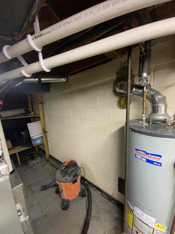 Conducted assessment for new tankless water heater installation in basement utility room. Current American standard tank-type water heater is non-operational and will be replaced with a new tankless unit. Evaluated existing plumbing infrastructure, including PVC piping and venting requirements, and marked installation location on wall for upcoming work.