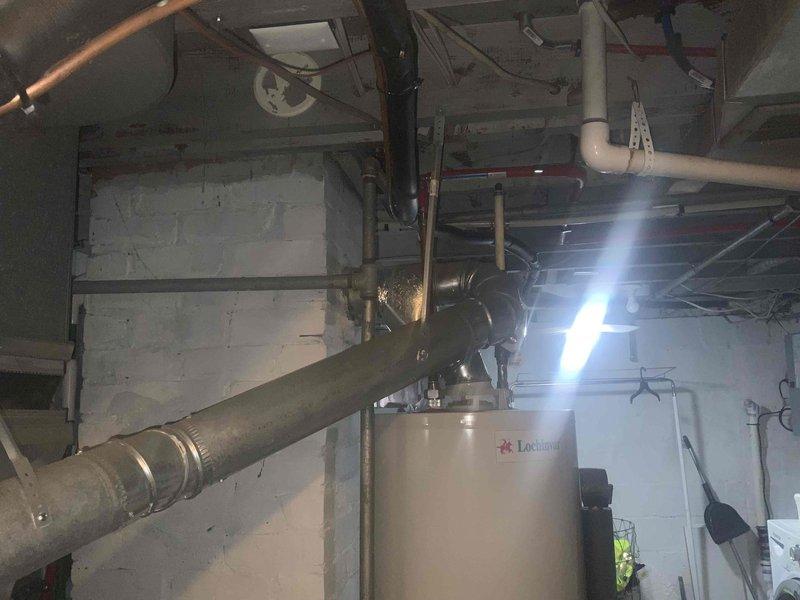 Performed diagnostic assessment on non-functioning Lochinvar water heater in utility room with associated plumbing and ventilation systems. Identified unit appears to be a commercial-grade installation with multiple connection points requiring evaluation. Documented existing configuration including PVC venting, supply lines, and proximity to Dyna-Glo furnace to prepare comprehensive replacement estimate.