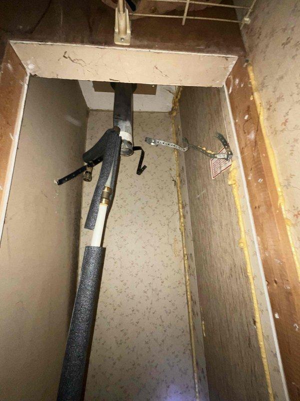 Conducted inspection of mobile home water heater installation site where customer had already removed the existing unit. Observed exposed wall cavity with visible plumbing connections including an insulated pipe. Noted electrical junction box present in the confined space. Site requires standard (non-tankless) water heater replacement suitable for mobile home application.