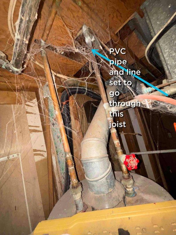 Conducted assessment of 20+ year old natural gas furnace located in basement for potential replacement. Performed visual inspection of installation area, noting unfinished plumbing space with exposed wooden joists and existing PVC drainage. Identified suitable pathway for new line set installation through existing joist structure to accommodate furnace and AC system replacement.