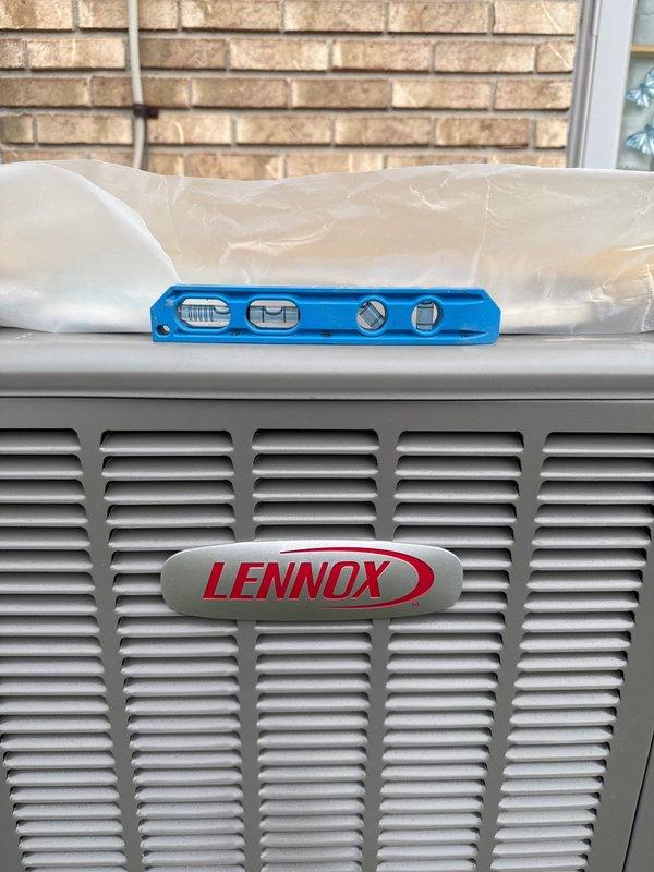 Responded to a callback for an outdoor air conditioning unit that was severely unlevel (3-4 inches). Verified the issue using a spirit level on the Lennox unit and corrected the installation to ensure proper leveling, as the original placement was in violation of installation standards. Documentation photos were taken of the correction for service records.