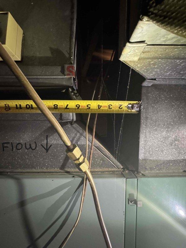 Conducted estimate for replacement of 50+ year old natural gas furnace and AC system located in basement. Current equipment is still operational but aged well beyond expected service life. Observed existing ductwork with 8" connections and noted the flow direction markings. System includes teal-colored furnace housing with metal ductwork secured by yellow strapping.