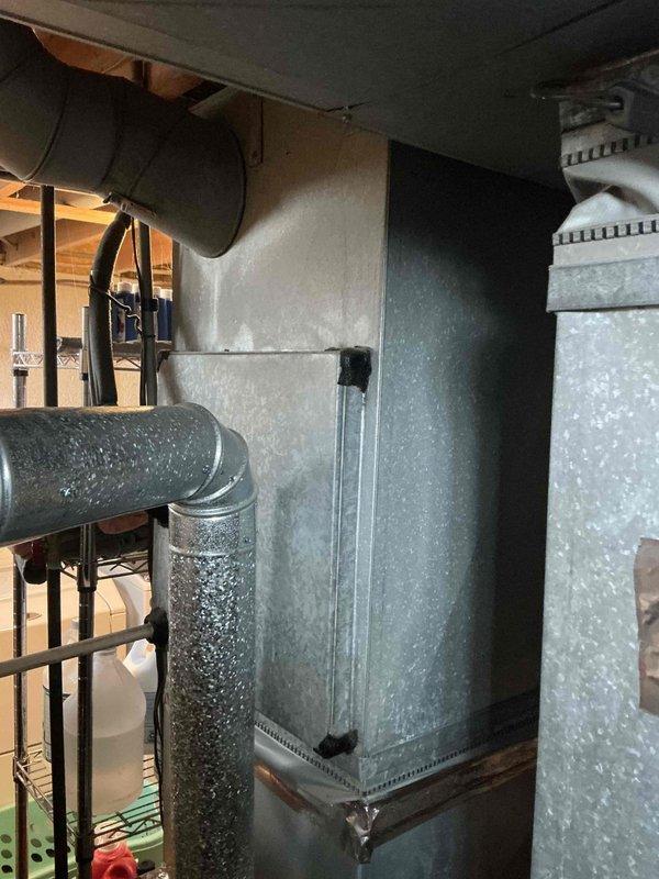 Conducted assessment of existing furnace system in tight utility space to determine IAQ solution compatibility. Inspected main furnace unit with connected galvanized metal ductwork and exhaust flue in basement area. Evaluated space constraints and current configuration to prepare appropriate indoor air quality improvement options.