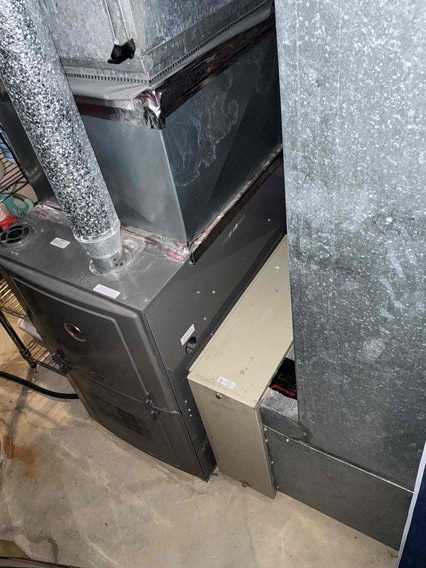 Conducted assessment of existing furnace system in tight utility space to determine IAQ solution compatibility. Inspected main furnace unit with connected galvanized metal ductwork and exhaust flue in basement area. Evaluated space constraints and current configuration to prepare appropriate indoor air quality improvement options.