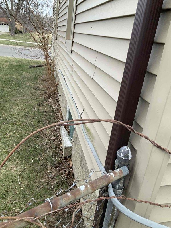 Performed comprehensive electrical inspection of residential main panel located in basement/utility area. Panel inspection revealed multiple circuit breakers with handwritten labeling including "GARAGE" and "220V" circuits. Exterior inspection identified service entrance configuration and utility connections, with documentation of all electrical distribution components via detailed photographs.