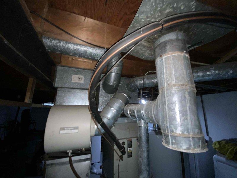 Conducted evaluation of 1998 natural gas furnace system located in basement. Unit is currently operational but approaching end of useful life at 25+ years. Inspection revealed aging ductwork with multiple connection points and a Honeywell humidifier component integrated into the system. Replacement options were presented to upgrade efficiency and reliability while utilizing existing utility connections.