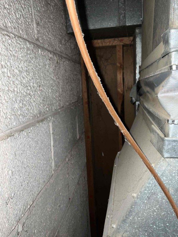 Conducted comprehensive evaluation of 16-year-old AC and heating system for potential replacement. Inspected outdoor condenser unit mounted on concrete pad with associated electrical connections and refrigerant lines. Examined indoor ductwork configuration and copper line set routing in utility access area. Documented system condition and installation constraints to prepare detailed replacement estimate as requested by customer.