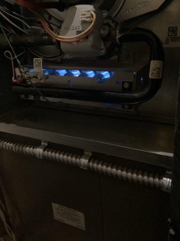 Performed scheduled Air Care Heating and Cooling maintenance service. Inspected gas burner system with visible blue flames indicating proper operation, and examined control module and ignition system components. Found outdoor condenser coil severely clogged with dirt and debris, which was thoroughly cleaned to restore proper airflow and system efficiency.