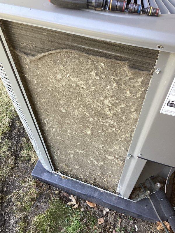 Performed scheduled Air Care Heating and Cooling maintenance service. Inspected gas burner system with visible blue flames indicating proper operation, and examined control module and ignition system components. Found outdoor condenser coil severely clogged with dirt and debris, which was thoroughly cleaned to restore proper airflow and system efficiency.