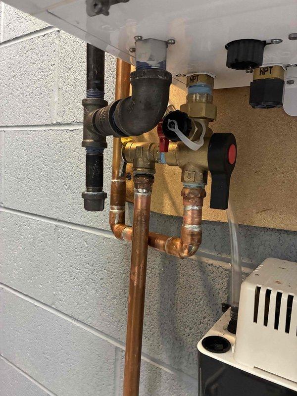 Responded to service call for tankless water heater leaking at supply and drain valve manifold. Inspection revealed significant corrosion and oxidation on copper elbow joint and fittings. Replaced damaged copper piping sections and valve manifold assembly to resolve leak issue.