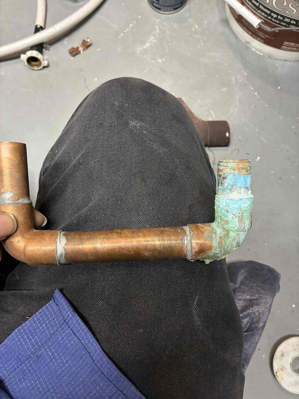 Responded to service call for tankless water heater leaking at supply and drain valve manifold. Inspection revealed significant corrosion and oxidation on copper elbow joint and fittings. Replaced damaged copper piping sections and valve manifold assembly to resolve leak issue.