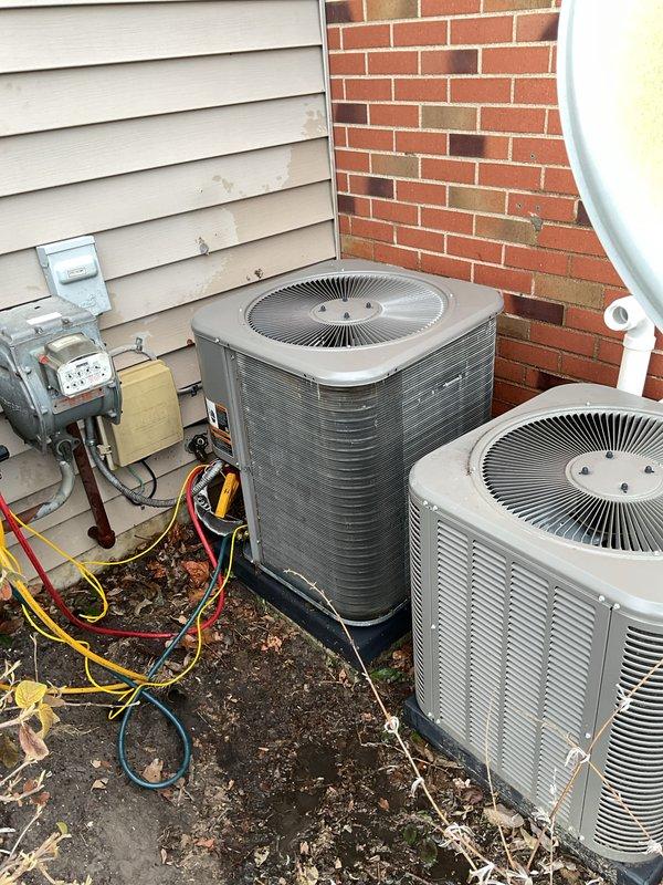Performed annual maintenance on two outdoor AC condensing units. Inspected older unit showing significant dirt accumulation on coils and exterior casing with possible corrosion, while the newer unit was in better condition. Maintenance included checking service lines (yellow, red, blue) connected to electrical disconnect box, and noted replacement filters/pads are needed.