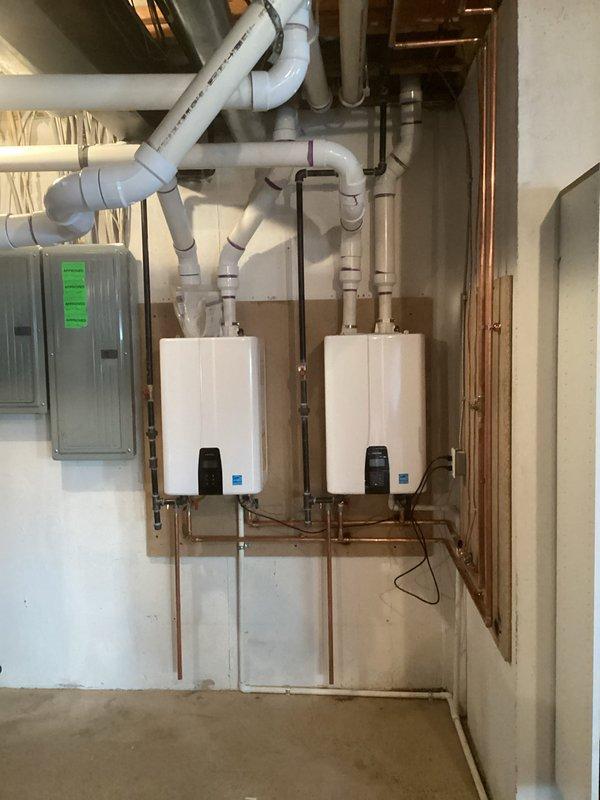 Successfully installed dual tankless water heaters with complete mechanical reconnection of all necessary plumbing components. System features copper supply lines connecting to the wall-mounted units, with proper PVC venting installed overhead according to manufacturer specifications. All electrical connections were properly established and the system was tested for optimal functionality.