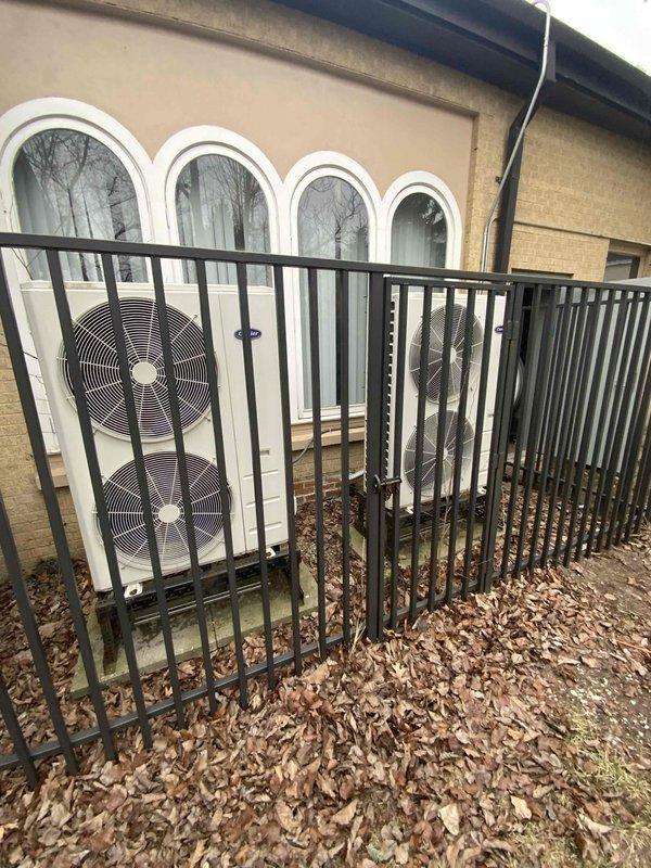 Conducted assessment for replacement of two non-functioning mini-split systems at church community building. Inspection revealed dual outdoor condenser units with dual fans positioned on concrete pads against exterior wall, enclosed in security fencing. Recommended replacement of both aging units to restore proper climate control functionality.