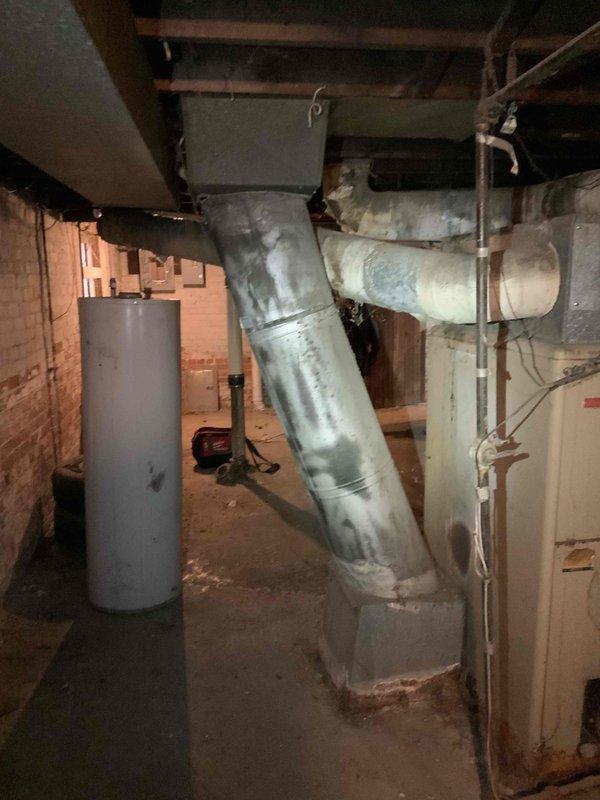 Conducted inspection of aging furnace system in duplex basement that is barely operational. Assessment included examination of existing ductwork, which shows significant wear with dusty metal surfaces and inconsistent insulation on diagonal runs. Evaluation also included adjacent water heater and current ventilation configuration to prepare comprehensive replacement estimate for both furnace and potential AC installation.