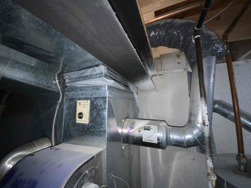 Conducted a full system estimate on an aging 10-year-old AC unit that requires immediate replacement. Inspected the existing installation which includes a furnace with exposed control board, metal ductwork with multiple connection points, and adjacent water heater system. Documented the confined installation space and current configuration to develop appropriate replacement options for the customer's right-away timeline.