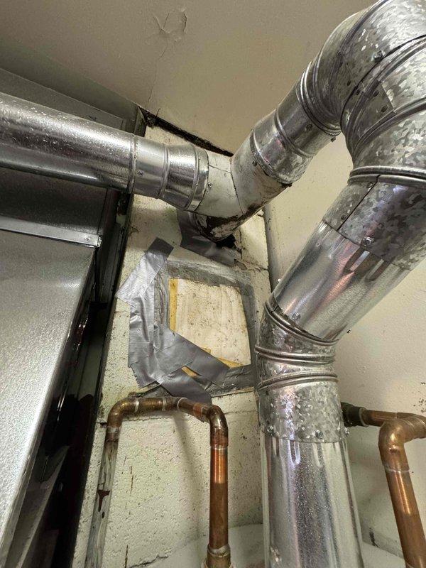 Inspected non-functional A.O. Smith water heater (installed 4-14-15) for replacement. Observed deteriorated ductwork connection and makeshift repairs with duct tape at wall penetration. Took measurements of existing tanked unit and surrounding installation constraints to prepare estimate for standard water heater replacement.