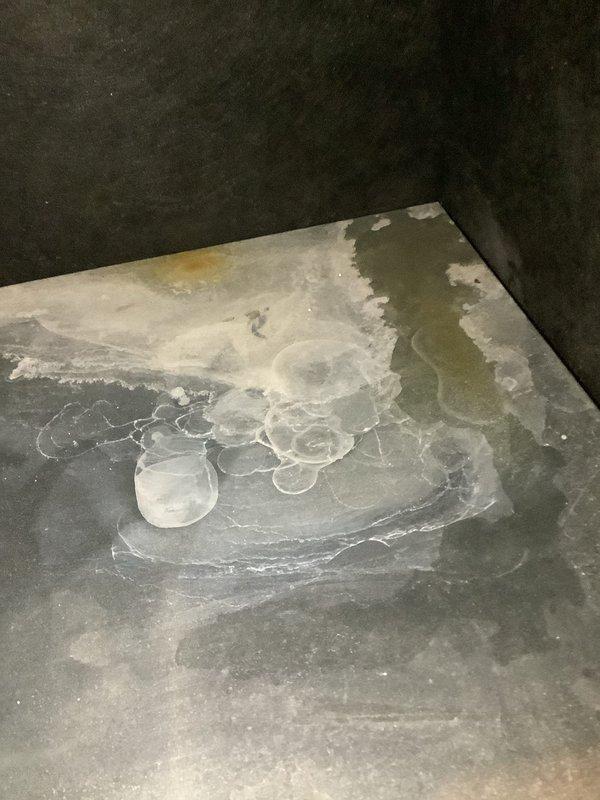 Performed routine Air Handler Maintenance inspection and identified significant mineral deposits on floor surface beneath unit, likely from condensate drainage issues. Documented substantial rust formation along heat exchanger/coil junction with housing, indicating potential moisture intrusion and ongoing corrosion that may require future remediation.