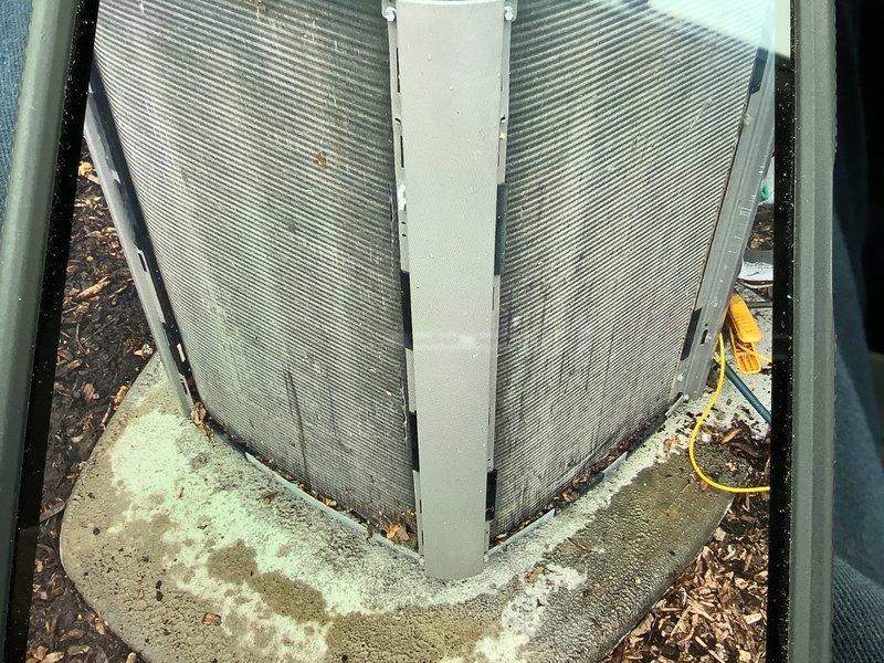Completed annual cooling maintenance on residential air conditioning system. Inspected outdoor condenser unit with V-shaped coil configuration, noting dirt accumulation on fins and algae growth on concrete pad. Replaced air filter and evaporator pads as requested, verified electrical connections, and documented equipment condition with photographs for service records.
