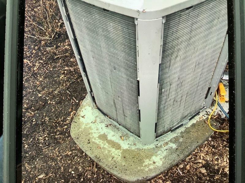 Completed annual cooling maintenance on residential air conditioning system. Inspected outdoor condenser unit with V-shaped coil configuration, noting dirt accumulation on fins and algae growth on concrete pad. Replaced air filter and evaporator pads as requested, verified electrical connections, and documented equipment condition with photographs for service records.