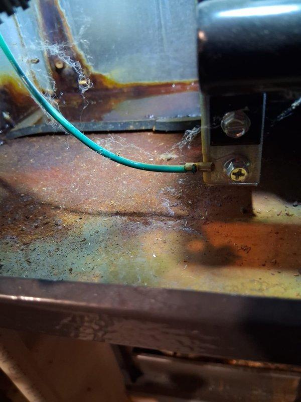 # Service Report

Responded to service call for 4+ year old furnace unit located in basement with reported no heat condition. Upon arrival, performed comprehensive system diagnostic to identify root cause of heating failure.

Inspection revealed extensive rust and corrosion throughout critical furnace components, including significant oxidation on base plate and interior metal surfaces. Corrosion patterns indicated prolonged moisture exposure and humid operating conditions. Green grounding wire connection to terminal showed proper electrical bonding, though surrounding metal exhibited heavy rust contamination with orange and brown discoloration.

Examined condensate management system and identified rust staining on drain pan surfaces with characteristic orange-brown streaking along curved edges and flat surfaces. Corrosion patterns suggested ongoing moisture accumulation issues. Verified condensate drain line connections and mounting hardware securing drainage components.

The severity