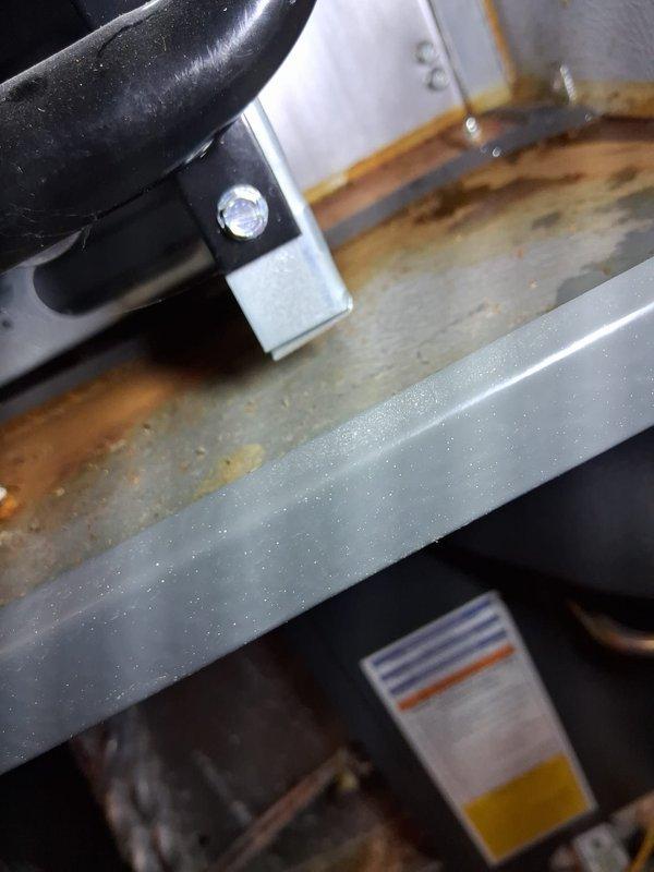 # Service Report

Responded to service call for 4+ year old furnace unit located in basement with reported no heat condition. Upon arrival, performed comprehensive system diagnostic to identify root cause of heating failure.

Inspection revealed extensive rust and corrosion throughout critical furnace components, including significant oxidation on base plate and interior metal surfaces. Corrosion patterns indicated prolonged moisture exposure and humid operating conditions. Green grounding wire connection to terminal showed proper electrical bonding, though surrounding metal exhibited heavy rust contamination with orange and brown discoloration.

Examined condensate management system and identified rust staining on drain pan surfaces with characteristic orange-brown streaking along curved edges and flat surfaces. Corrosion patterns suggested ongoing moisture accumulation issues. Verified condensate drain line connections and mounting hardware securing drainage components.

The severity