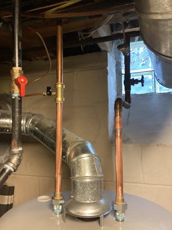 # Plumbing Install - Tanked Water Heater

## Job Description

Completed installation of a new 50-gallon residential tanked water heater with ICON System gas control valve. Removed existing water heater unit and properly positioned new tank on stable platform in basement mechanical room. Connected copper supply and discharge piping with appropriate shut-off valves and pressure relief components. Installed gas line connection to control valve assembly and verified all fittings for proper seal integrity. Mounted ICON System gas control unit featuring adjustable temperature settings (OFF, PILOT, LOW, HOT, VERY HOT) with integrated status indicator and electronic ignition system. Configured pilot light operation and tested ignition sequence for reliable startup. Secured all piping with metal clamps and brackets to ensure structural stability and code compliance. Verified proper venting configuration and clearances around unit. Tested water heater operation through multiple heating cycles to