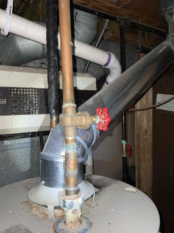 # Water Heater Replacement Estimate

Responded to service call for leaking water heater in residential basement. Upon inspection, found 10-year-old conventional storage tank water heater with active leak originating from bottom of tank, indicating internal tank failure. Observed moisture staining on concrete floor beneath unit and corrosion evidence on tank base. Documented existing installation including copper supply lines with shutoff valve, brass fittings, and connection to PVC venting system. Assessed household hot water demand for three occupants and evaluated existing plumbing configuration including gas supply line routing and clearance requirements. Photographed current equipment setup showing water heater positioned adjacent to furnace unit with overhead exposed joists and existing piping infrastructure. Provided comprehensive estimate for replacement with standard-efficiency residential water heater appropriate for household size and budget considerations, including removal 