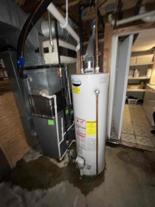 # Water Heater Replacement Estimate

Responded to service call for leaking water heater in residential basement. Upon inspection, found 10-year-old conventional storage tank water heater with active leak originating from bottom of tank, indicating internal tank failure. Observed moisture staining on concrete floor beneath unit and corrosion evidence on tank base. Documented existing installation including copper supply lines with shutoff valve, brass fittings, and connection to PVC venting system. Assessed household hot water demand for three occupants and evaluated existing plumbing configuration including gas supply line routing and clearance requirements. Photographed current equipment setup showing water heater positioned adjacent to furnace unit with overhead exposed joists and existing piping infrastructure. Provided comprehensive estimate for replacement with standard-efficiency residential water heater appropriate for household size and budget considerations, including removal 