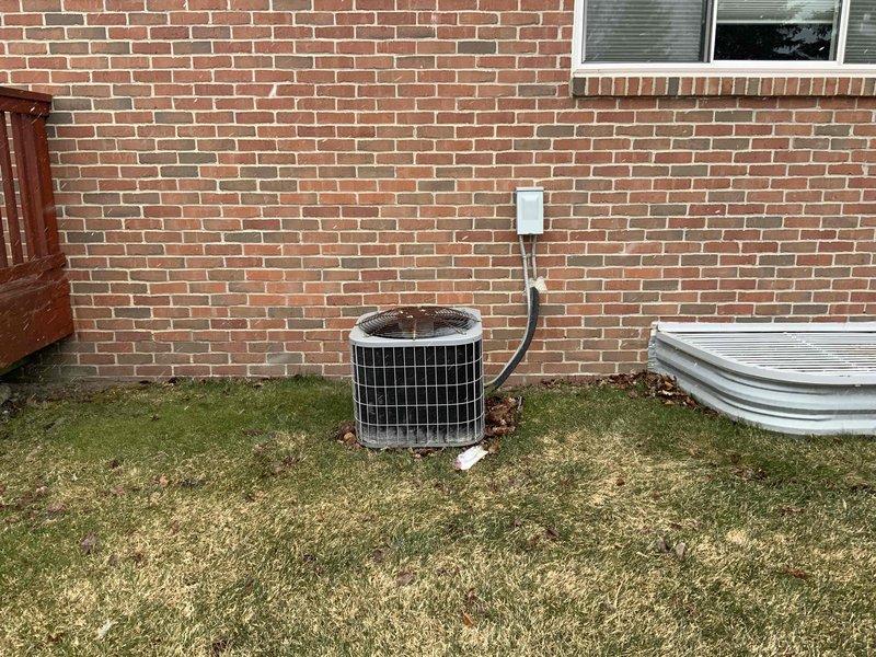 # HVAC Estimate - Full System Summary

Completed comprehensive estimate for full HVAC system replacement on 2003 residential installation. Evaluated existing natural gas forced air furnace and air conditioning system in ranch-style home with brick exterior. Documented current outdoor condenser unit condition, including coil assembly, electrical disconnect, and refrigerant line routing along exterior wall. Assessment included photographic documentation of existing equipment placement, electrical connections, and site conditions for proper system sizing and installation planning.