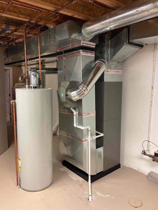 # HVAC Complete System Installation

Successfully completed installation of a complete HVAC system consisting of a 90,000 BTU furnace and 3-ton air conditioning unit with rear discharge configuration. The Lennox furnace was professionally installed in the basement mechanical room with proper clearances and code-compliant specifications. Integrated a humidifier into the system for enhanced indoor air quality control. Reconnected all existing utilities and established proper condensate drainage using white PVC piping. 

The installation included silver flexible ductwork connections from the furnace with metallic elbow transitions for optimal airflow distribution. All mechanical, electrical, and HVAC permits were obtained prior to installation to ensure full code compliance. System commissioning verified proper operation of both heating and cooling components. The equipment was installed with appropriate safety clearances from the existing water heater and other mechanical equipment in th