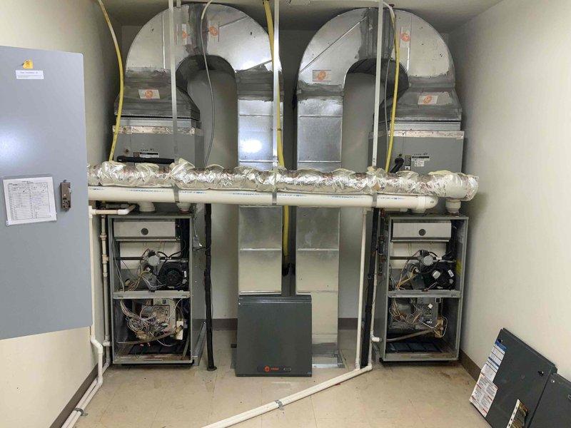 Completed site assessment of commercial building with residential units to provide updated quote for furnace replacement. Inspected existing HVAC equipment on second floor, including 7 furnaces, 7 air conditioning units, and multiple hot water tanks. Documented current furnace installations, noting dual furnace configurations with gas line connections, electrical panels, and ductwork systems. Photographed mechanical room equipment to support quote preparation for 2-unit furnace replacement project.