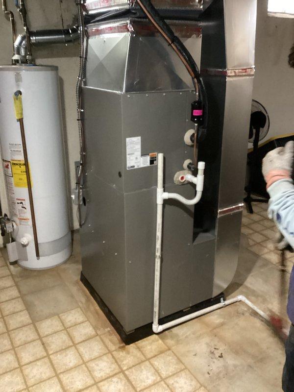 Completed warranty replacement installation of ML180 furnace unit in residential basement utility room. Installed new gray cabinet-style furnace with proper venting using white PVC piping, connected condensate drainage lines, and verified all ductwork connections including metallic flexible ducts. Ensured proper refrigerant line connections with insulation, confirmed blower compartment operation, and verified all safety labels and manufacturer specifications are visible and intact. Old unit requires return for warranty tagging processing.
