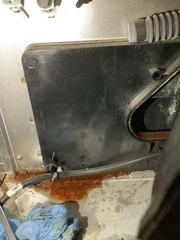 Responded to service call for furnace leaking water in basement location. Upon inspection, discovered moisture accumulation on interior components and visible water damage on concrete floor beneath unit. Identified condensate drainage issue with evidence of rust and corrosion on lower panels. Inspected condensate drain system, blower assembly, and evaporator coil area where moisture was present. Documented equipment condition showing dust accumulation and signs of improper drainage. Advised on necessary repairs to condensate removal system to prevent continued water leakage and potential secondary damage to furnace components and surrounding area.