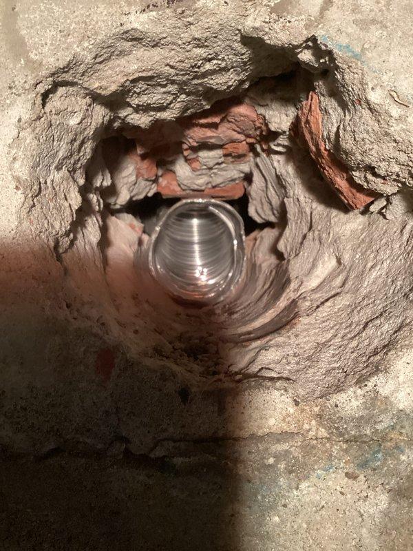 Responded to callback for chimney liner installation and water heater anode rod replacement. Assessed severely pitched roof with paneling surface near chimney and determined boom lift will be required for safe access due to low traction conditions. Attempted anode rod replacement to address rotten egg odor complaint, but Michigan basement configuration with low ceiling clearance (approximately 2-3 feet above tank) prevented removal of rod without full tank extraction. Documented site conditions with photos showing chimney penetration and clearance constraints. Recommended complete water heater removal and outdoor servicing to replace anode rod, as vertical space is insufficient for in-place rod extraction.