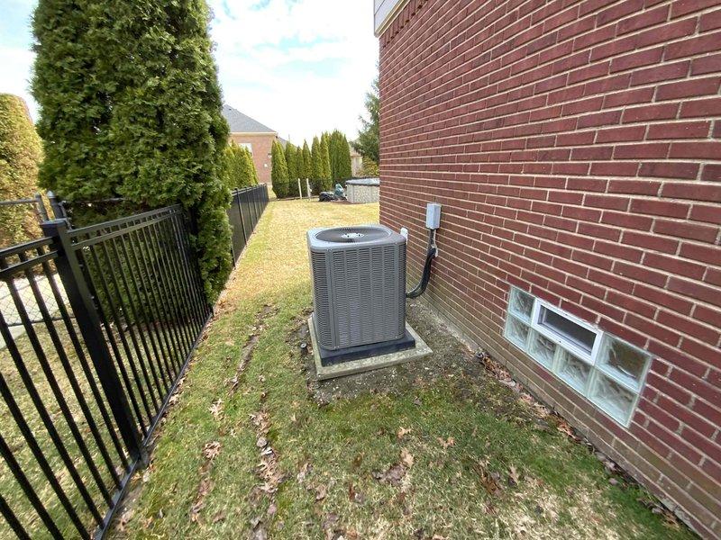 Completed comprehensive estimate for full HVAC system replacement at owner-occupied residence. Assessed existing 25-year-old furnace and 15-year-old air conditioning system, with exterior condensing unit located in side yard on concrete pad against brick structure. Documented current equipment configuration, electrical disconnect, and site conditions to provide replacement options for both heating and cooling equipment.