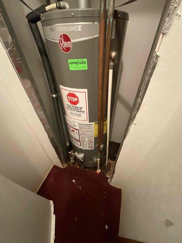Responded to service call for non-functioning older tanked water heater showing active water leakage at base. Assessed existing Rheem Performance unit installed in narrow utility closet with earthquake straps, copper supply lines, and metal vent pipe. Documented significant water pooling on floor beneath unit indicating tank failure. Provided estimate for removal of failed water heater and subsequent installation of new 40-gallon tanked unit with drip pan to prevent future water damage. Customer requested staged service approach: initial removal of existing failed unit to allow for water damage remediation and flooring repair by restoration company, followed by new water heater installation upon completion of repairs. Additional recommendation made for heat tape installation on exposed piping.