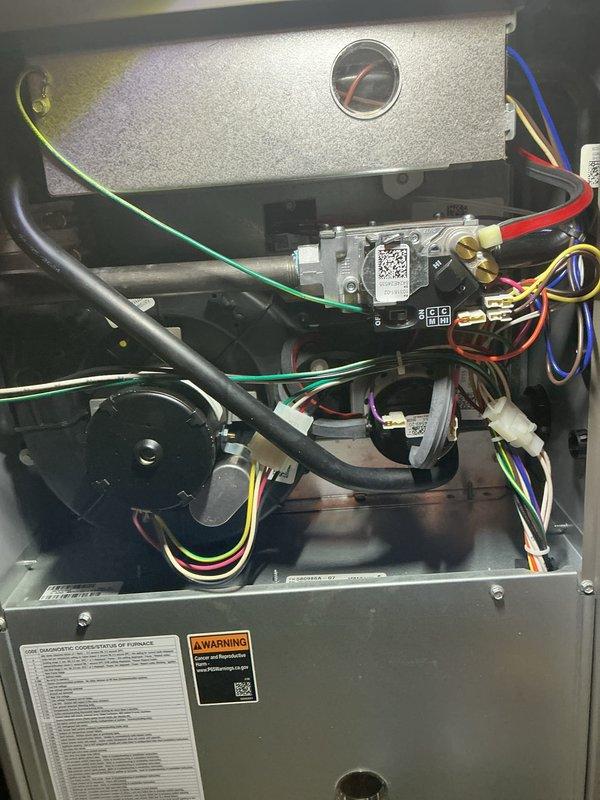 Completed annual heating maintenance and tune-up on furnace system. Performed comprehensive inspection of all internal components including blower motor assembly, heat exchanger, gas valve controls, electrical connections, and safety systems. Verified proper operation of pressure gauge, checked all wire connections and terminals for secure contact, and inspected burner assembly and ignition components. All systems tested and found operating within normal parameters. Unit photographed for service documentation showing accessible internal components and current system condition.