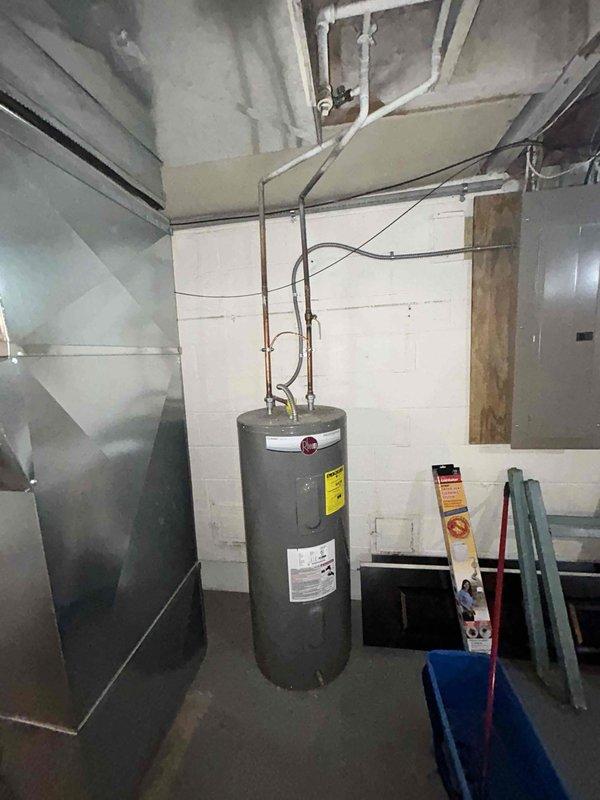 Completed site assessment for air conditioner replacement at residential property with 20-year-old existing system. Documented current HVAC installation in basement utility area, including existing Bryant furnace with PVC venting, ductwork configuration, and available clearances for new equipment installation. Photographed mechanical room layout showing water heater placement, existing duct routing, and workspace accessibility for upcoming AC system replacement.